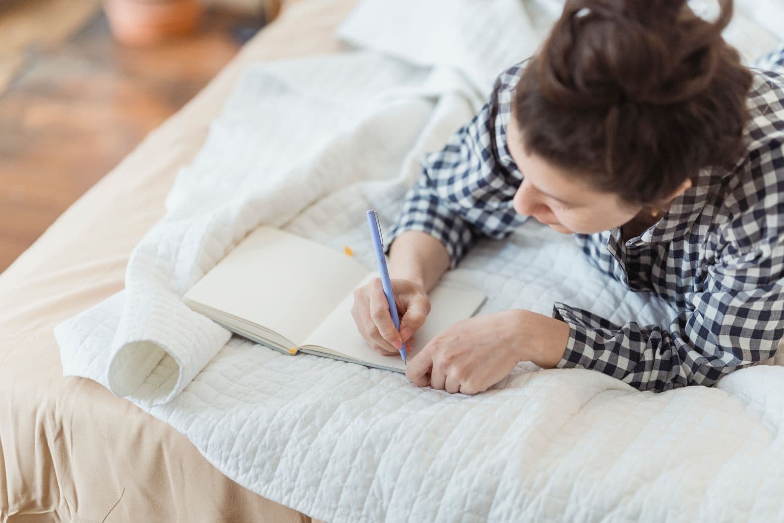A person writing in a notebook at home