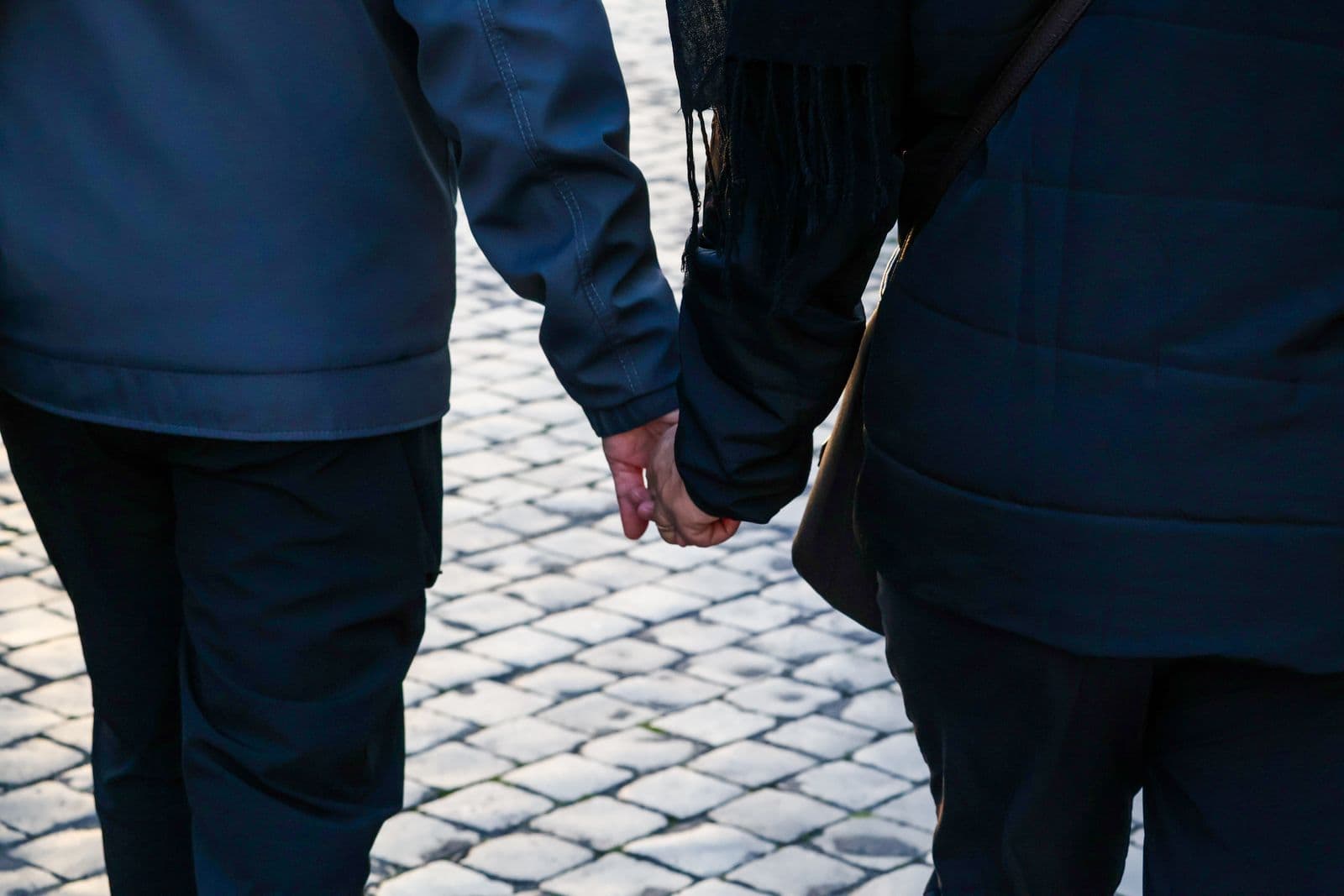 A couple walking hand in hand along a cobbled street